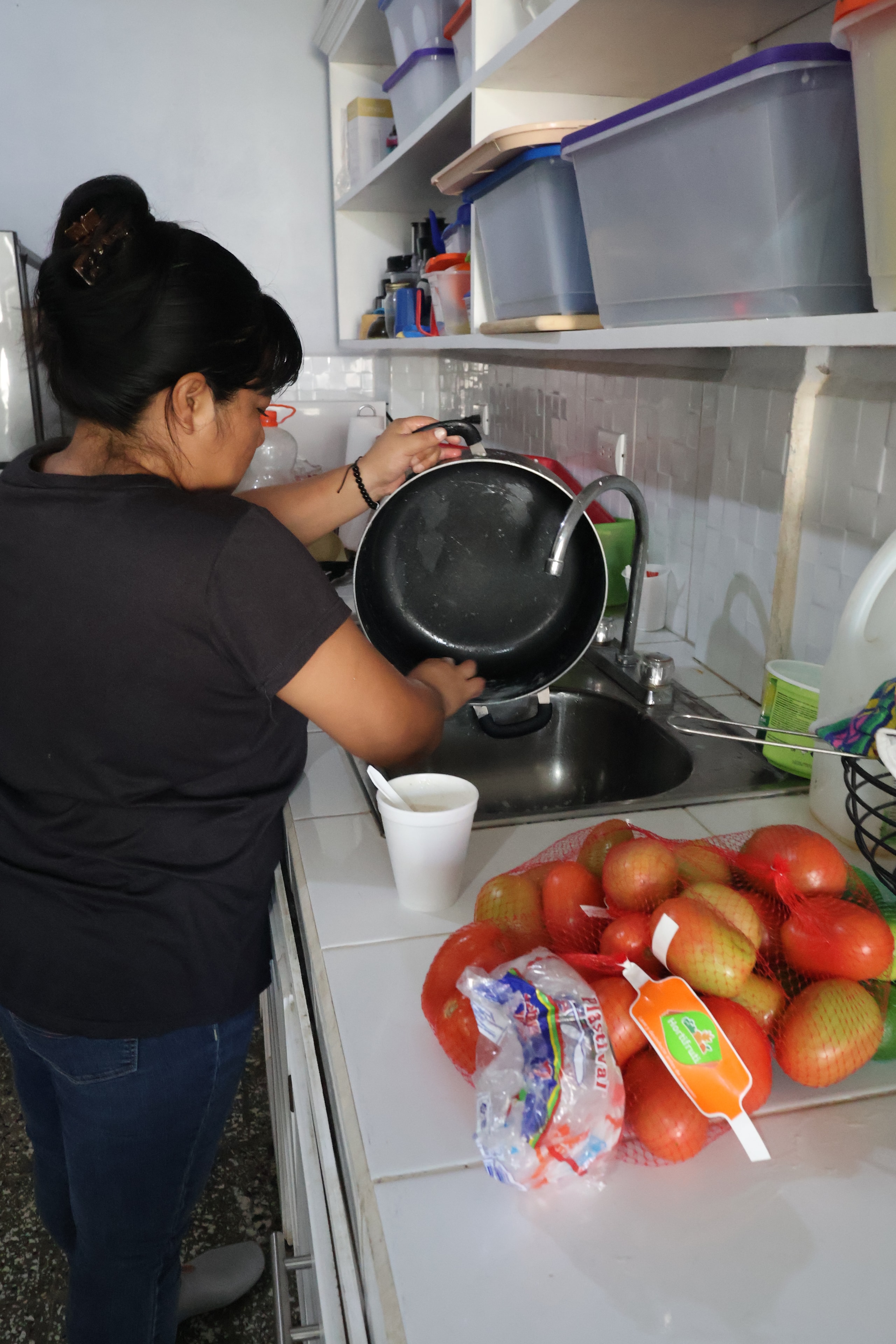 Woman washing a pan at a kitchen sink
