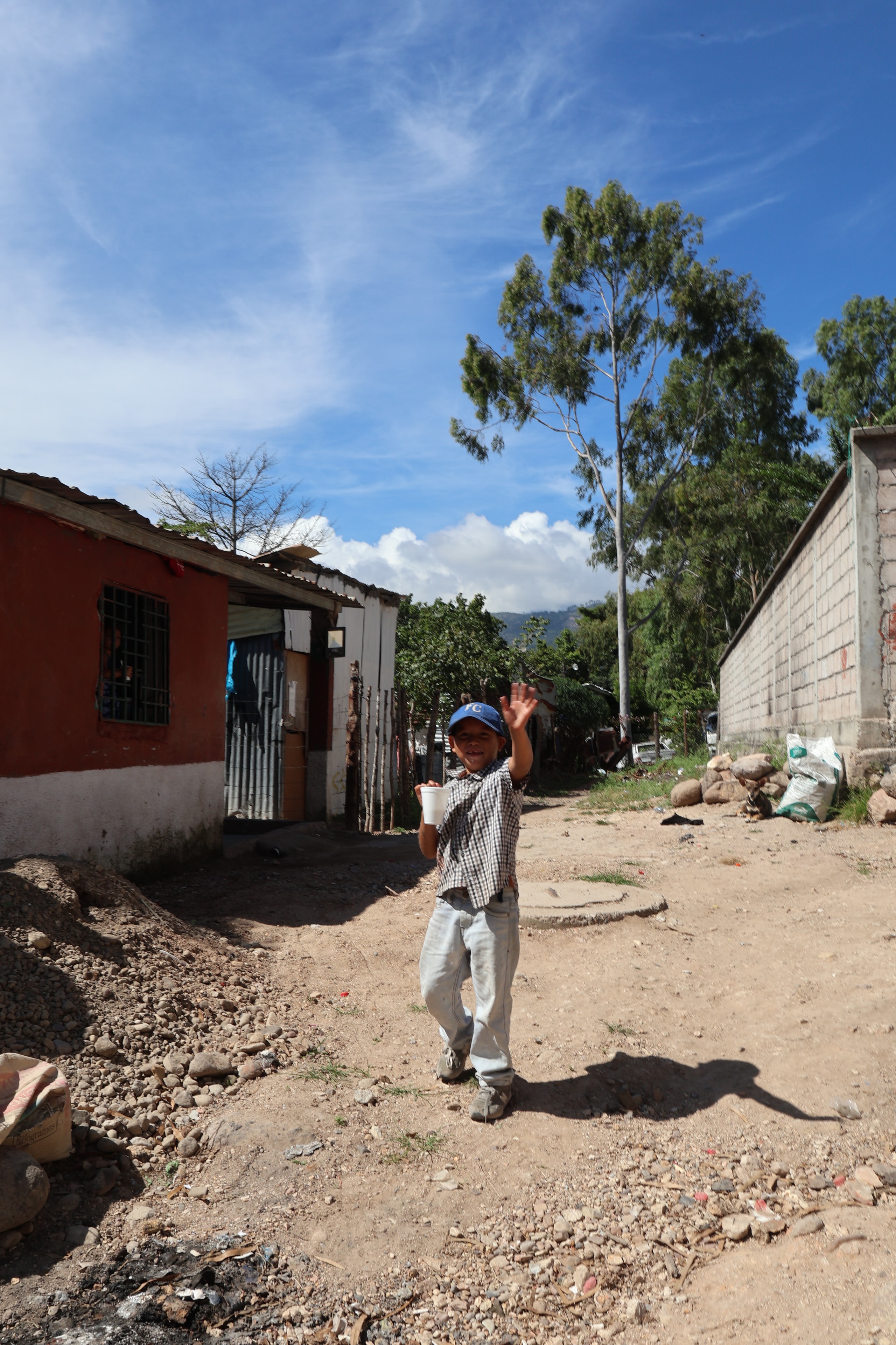 Boy waving on a rural village dirt road