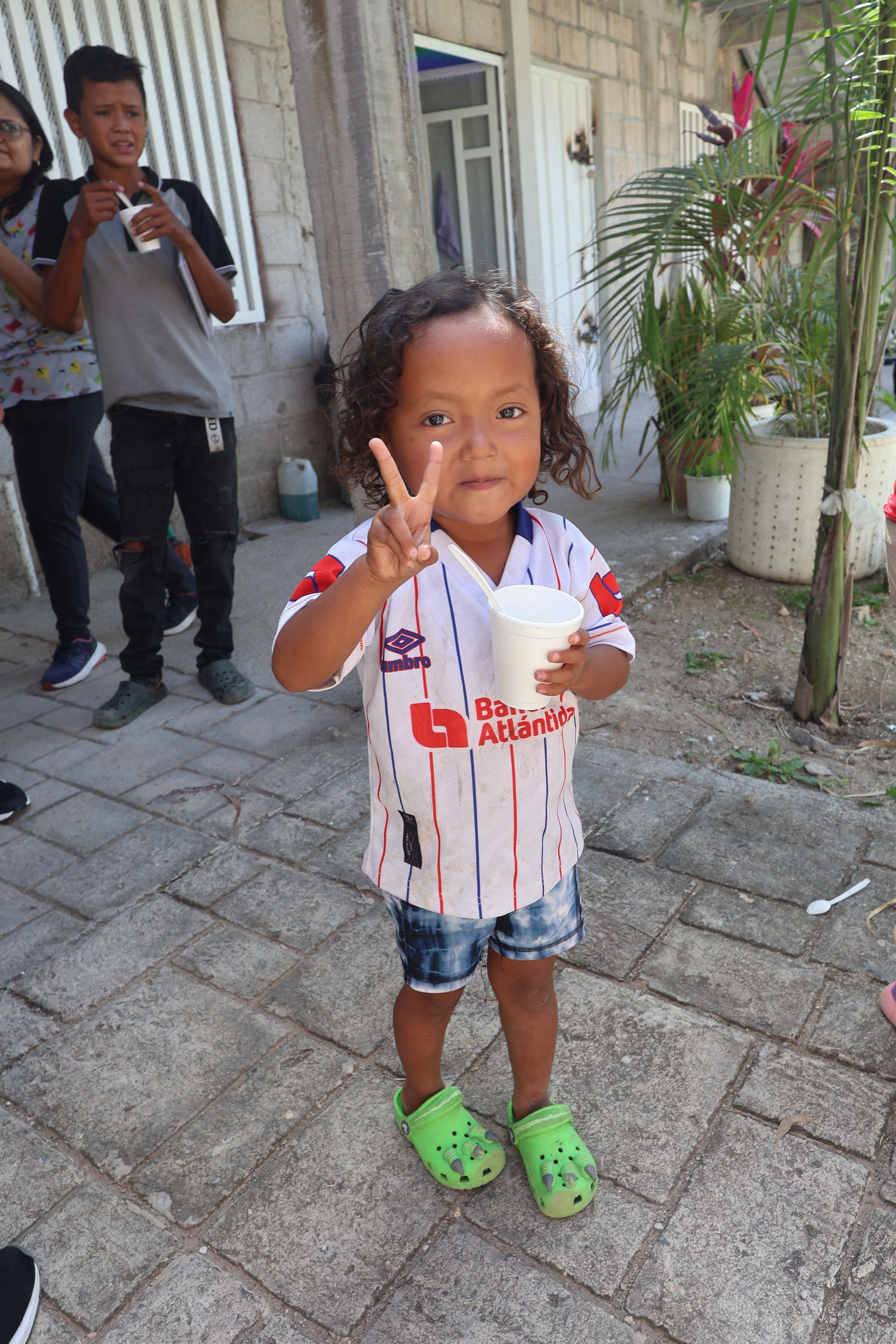 Toddler making a peace sign on an outdoor patio