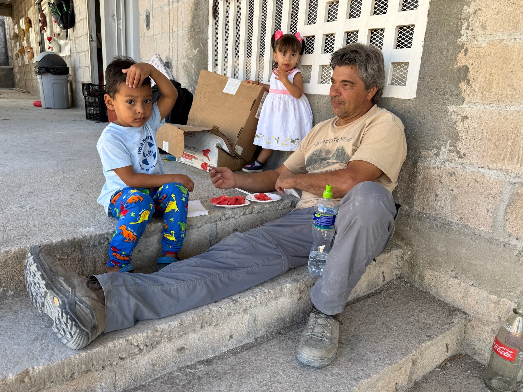 A man sharing a snack with children outdoors
