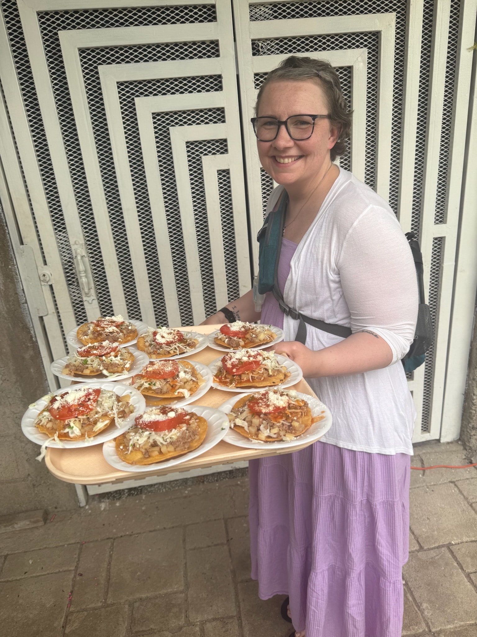 Woman serving loaded pizza slices outdoors