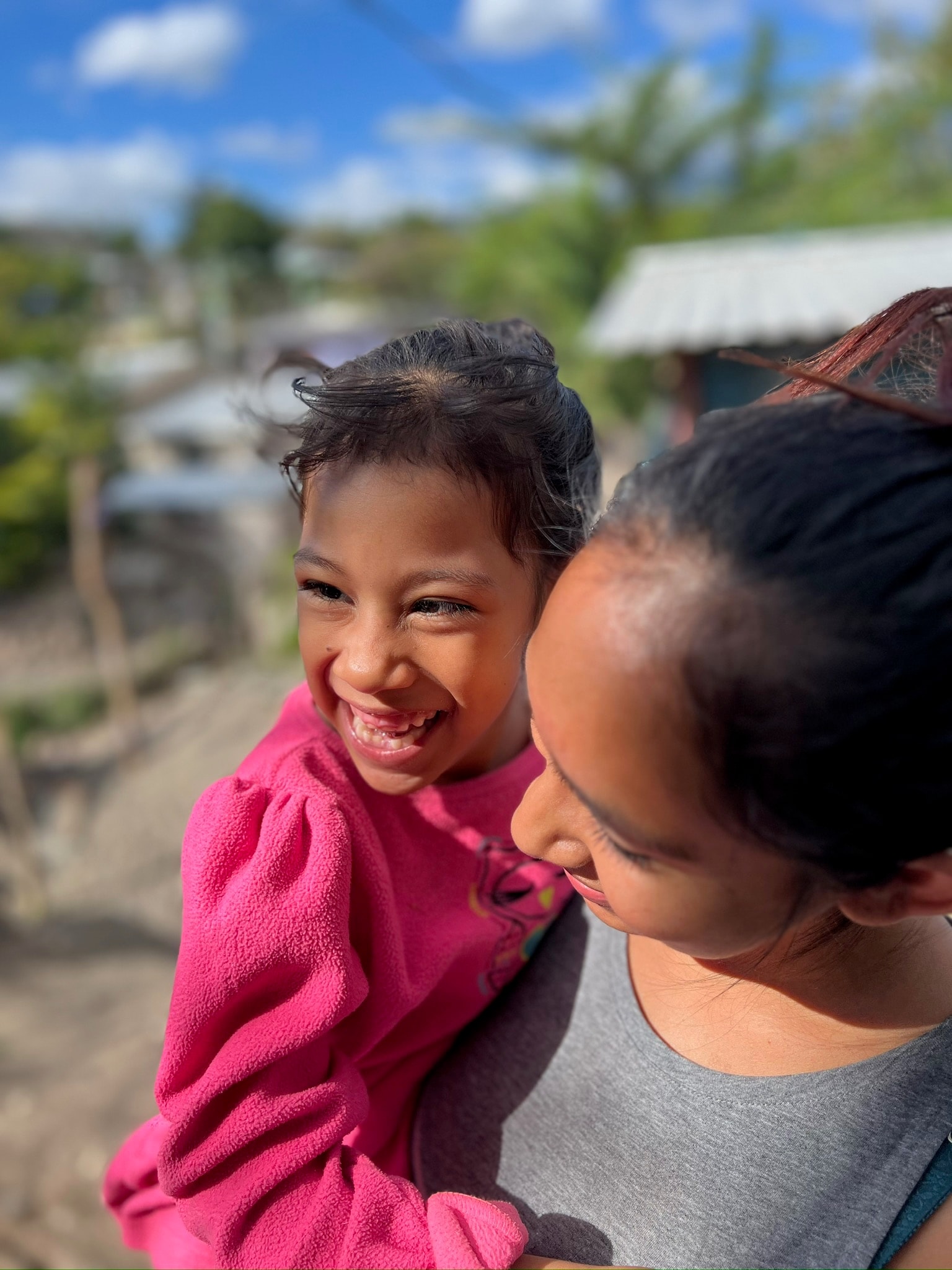 A child laughing with a parent in a rural Honduran village